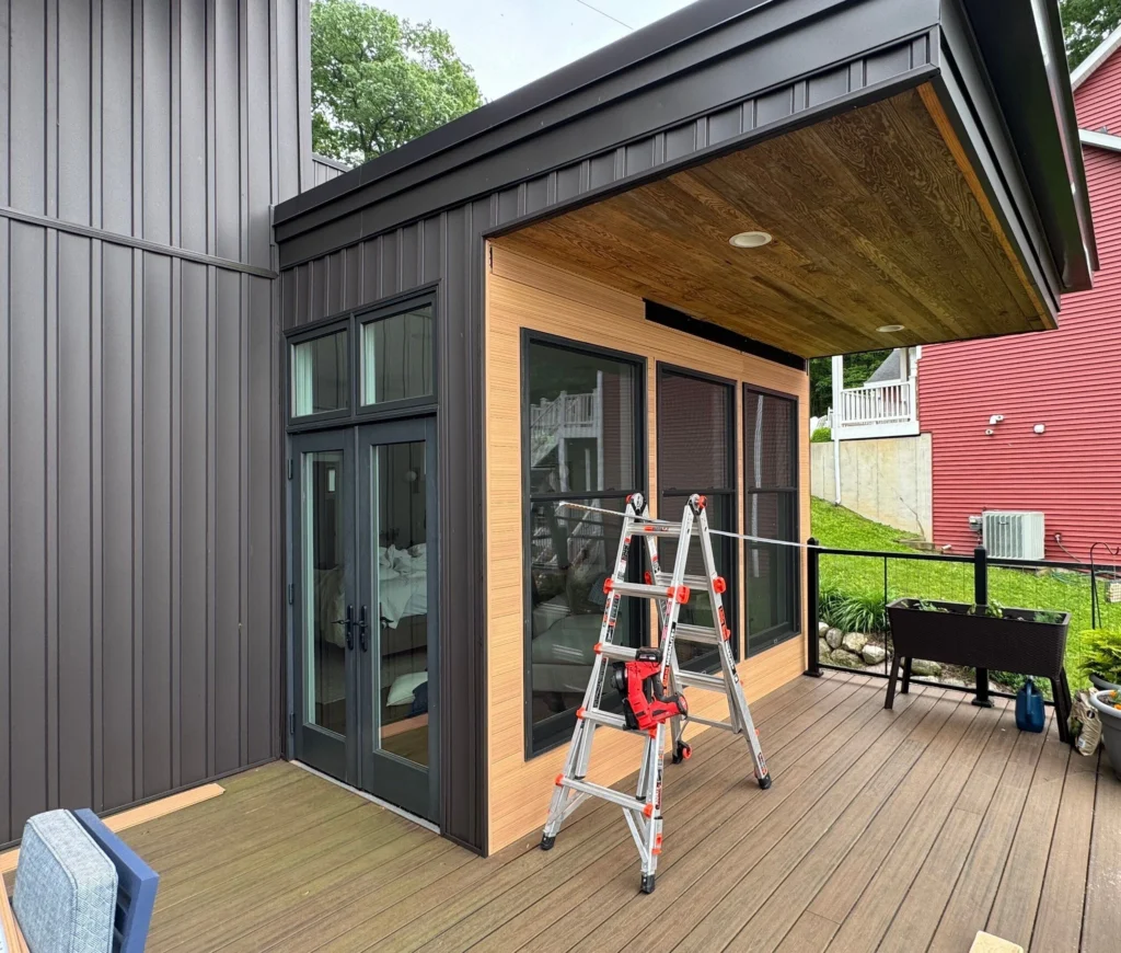 A new modern door system being installed on a Southwest Michigan home, showing the framing, tools, and exterior construction work in progress.